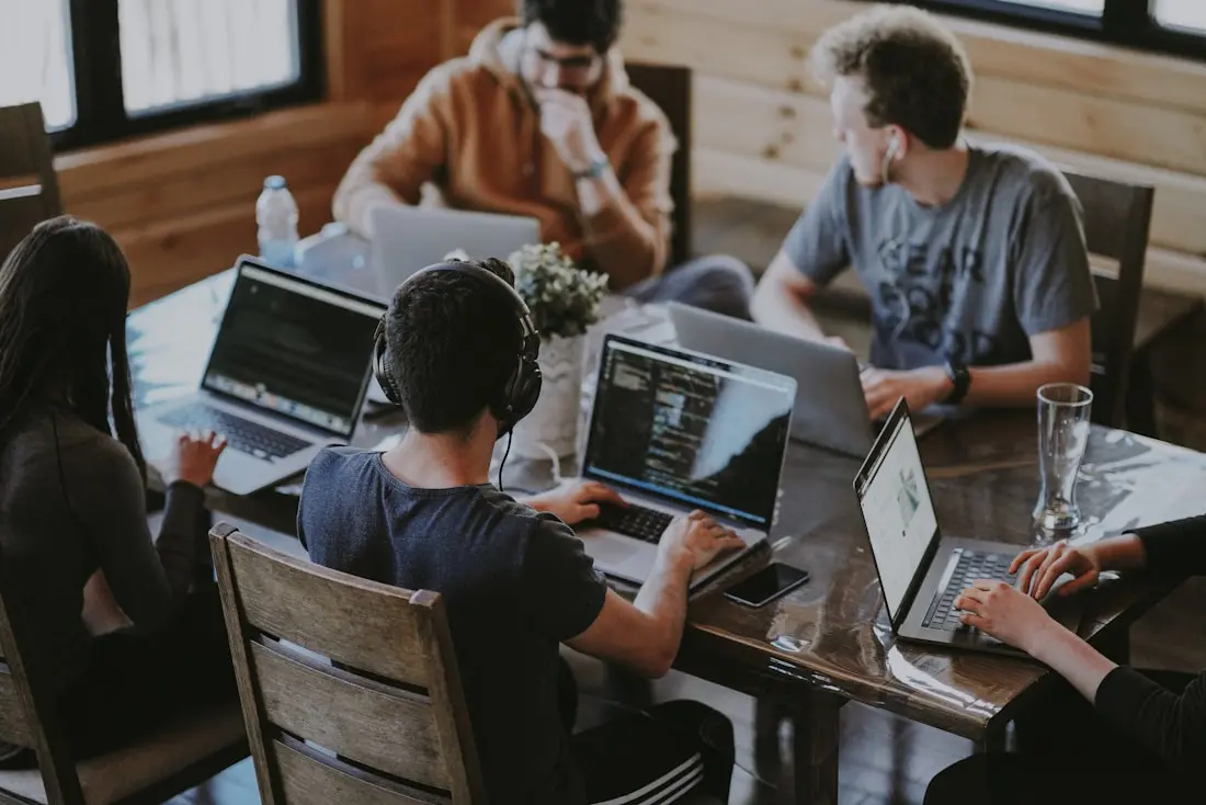 Team collaborating around a table with laptops in a bright office